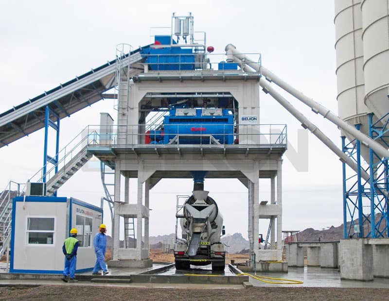 Concrete batching plant with mixer and workers.