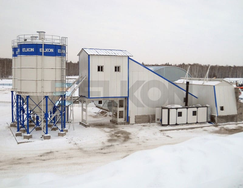 Concrete plant in snowy landscape with storage silo.
