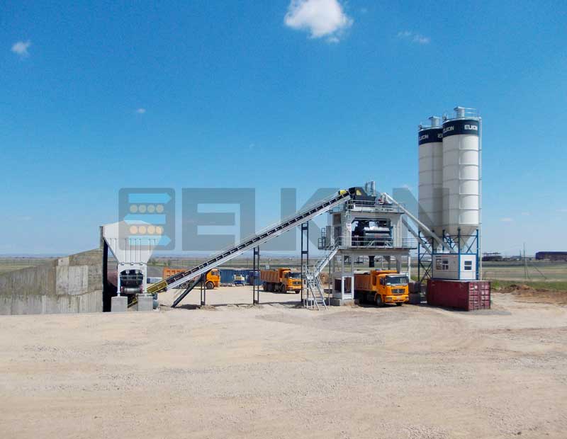 Concrete batching plant with trucks and silos.