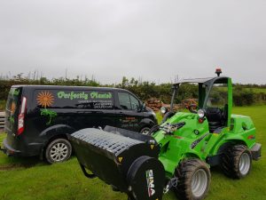 Garden maintenance van and green tractor in field.