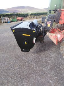 Agricultural implement attached to tractor in rural setting.
