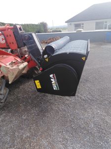 Red machinery with black attachment on gravel driveway.