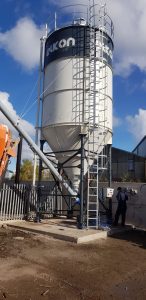 Large industrial silo and worker on-site inspection.