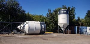 Eukon silos, one fallen, in industrial yard.