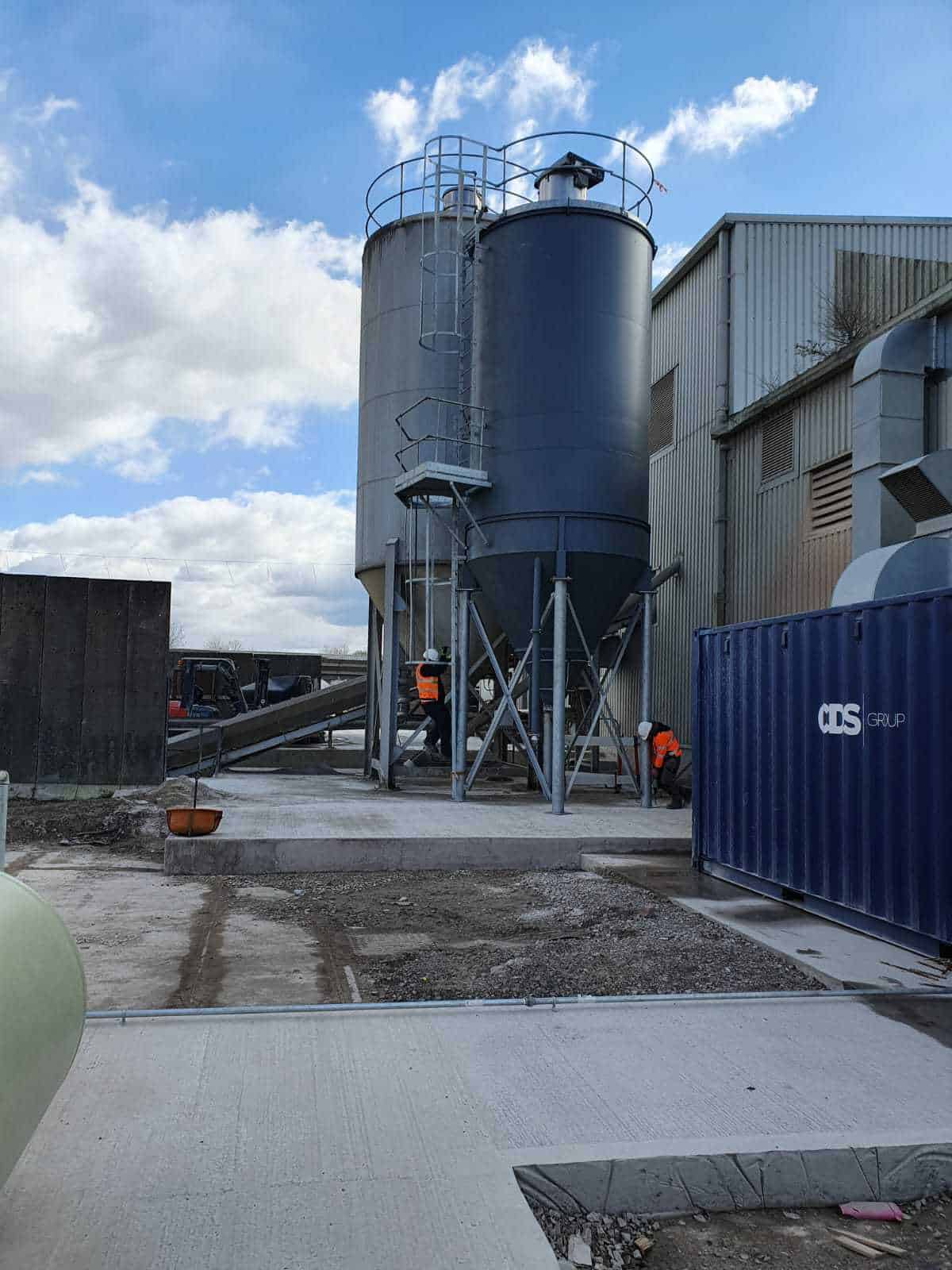 Industrial silos and workers at construction site.