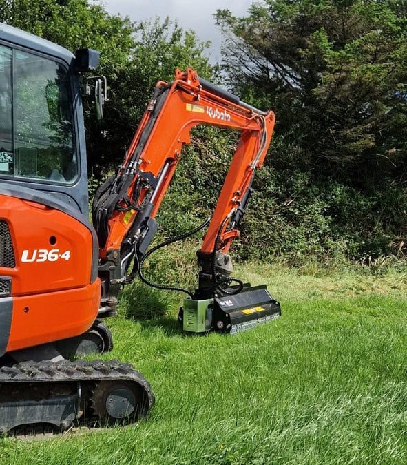 Orange excavator with brush cutter in grassy field.